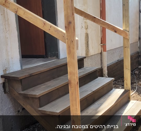 מדרגות עץ עם מעקה ליד כניסה לבית